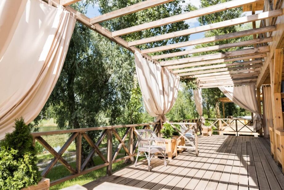 A sunny patio with movable boards for pergolas and draped curtains.
